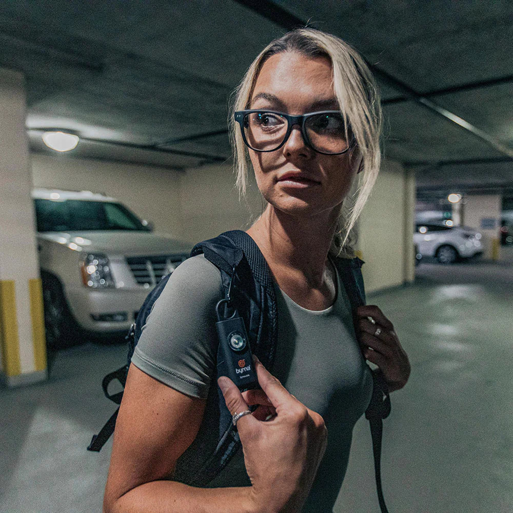 Woman with Byrna alarm on her backpack.