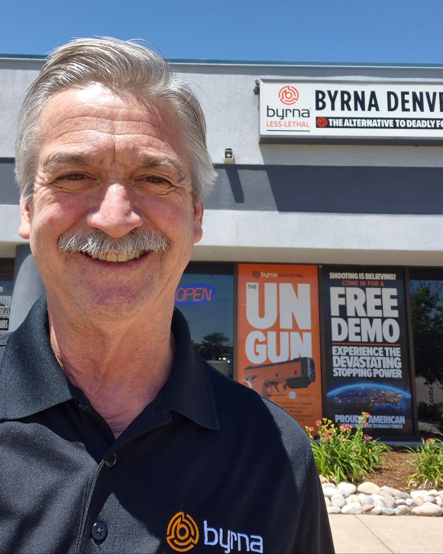 Byrna Denver owner, Bill, wearing a Byrna polo shirt standing in front of the Byrna Denver store.