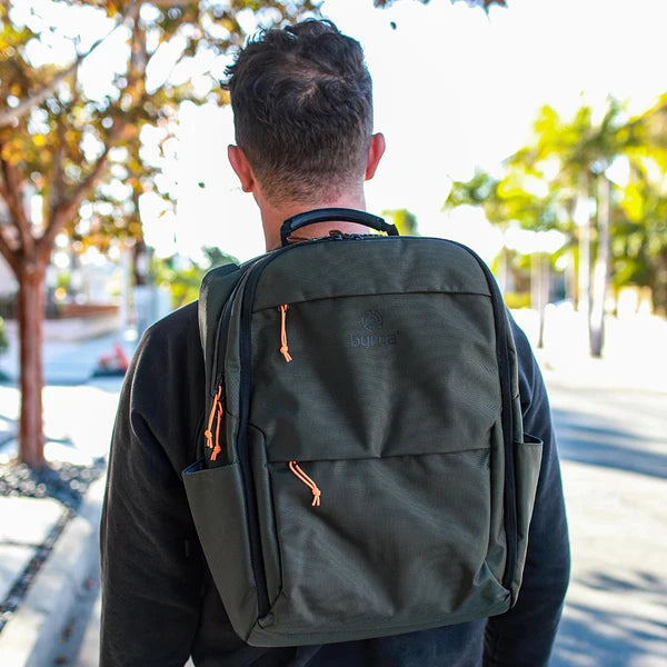 Person wearing a green backpack outdoors on a sunny day