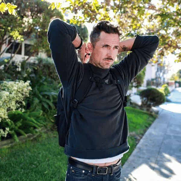 Man demonstrating how to pull the body armor out of the Ballistipac outfoors on a sunny day.