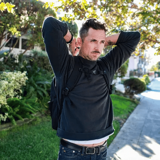 Man demonstrating how to pull the body armor out of the Ballistipac outfoors on a sunny day.