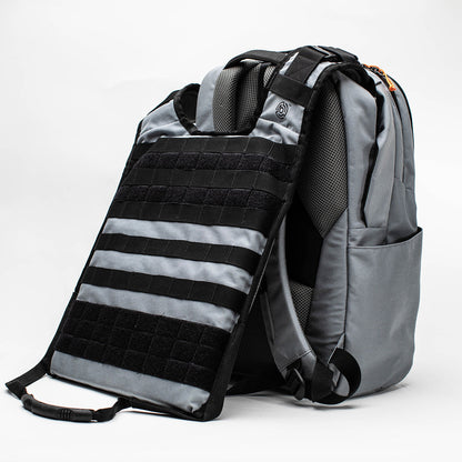 A gray and black tactical-style backpack shown on a white studio background, with a detachable black and gray body armor clipped onto the front.
