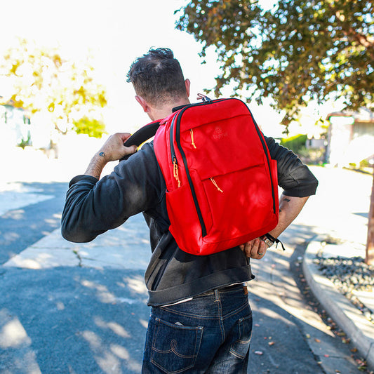 Person wearing a red backpack outdoors on a sunny day